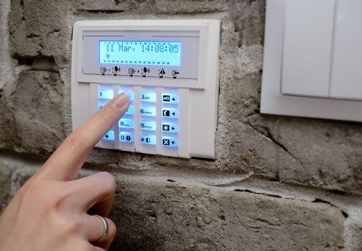 Closeup on woman's finger entering code into the keypad of the alarm system and activates the alarm